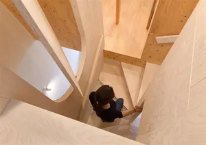 A person walking down a wooden staircase with a modern design.