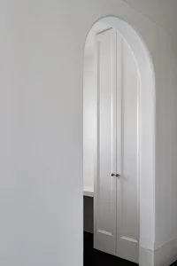 A modern white doorway interior with curved archway and minimalist design.