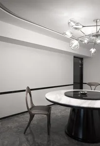A modern minimalist dining room featuring a round marble table and black-and-white color scheme.