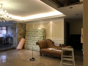 Living room with concrete flooring, marble columns, and renovation tools.