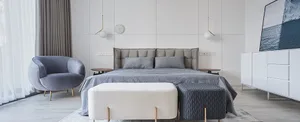 Modern minimalist bedroom with white walls, grey upholstered bed, and light grey curtains.