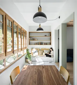 A minimalist dining room with wooden flooring, furniture, and shelves.