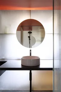 Modern bathroom featuring a circular mirror and ceramic sink.
