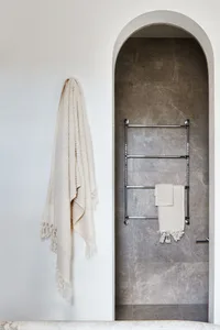 A modern bathroom with concrete walls, a towel rack, and a textured towel hanging on the wall.