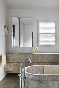 Modern bathroom with a freestanding marble bathtub, sink, and a mirror above the sink area.