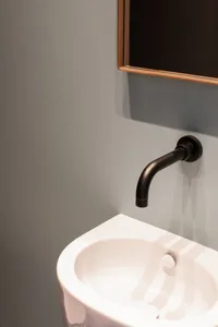 Modern black faucet mounted on a white ceramic bathroom sink.