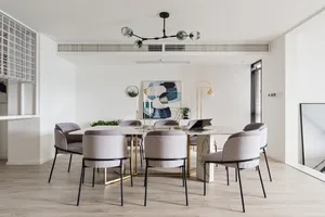 A modern dining room featuring a marble table and fabric chairs.
