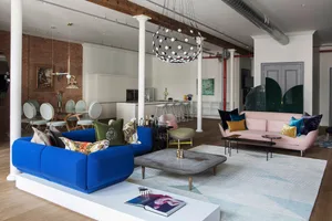 A modern interior design featuring a blue sofa, a pink sofa, and various decorative elements such as a coffee table, rugs, an