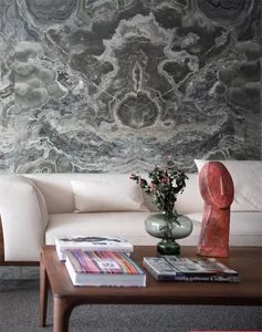 A modern living room featuring marble walls, a white leather sofa, and a wooden coffee table with books, a vase, and a sculpt