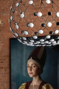 A modern metal chandelier with a geometric design hanging from a brick wall.