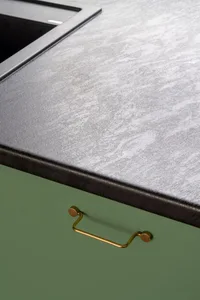 Modern kitchen featuring a stone countertop with a brass handle.