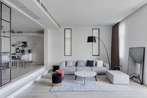 A modern minimalist living room with a grey sofa, a marble coffee table, and a large floor lamp.