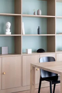 Modern minimalist workspace featuring wooden shelving and a black chair.
