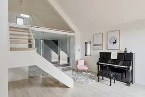 A modern music room featuring a black upright piano on a white wooden floor, with a pink armchair and a deer-themed poster on