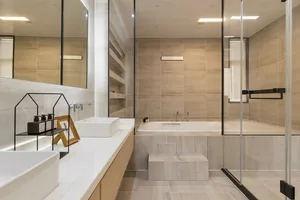 Modern residential bathroom featuring ceramic tile walls and a large bathtub.
