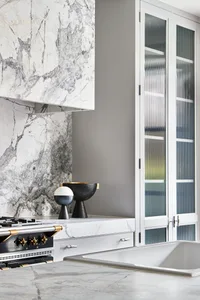 Luxurious residential kitchen featuring marble countertops and backsplash.