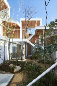 Modern residential building with white exterior, concrete walls, glass windows, and wooden accents.