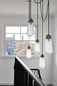 Modern staircase with glass railings illuminated by four frosted glass pendant lights with metal accents.