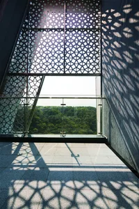 A modern interior design featuring a window with a patterned glass design and illuminated by sunlight casting a distinct shad