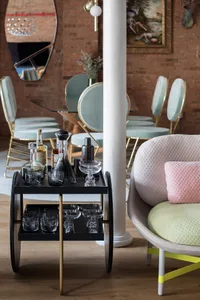 A modern living room with a vibrant green armchair, a sleek bar cart, and a mix of elegant furniture.