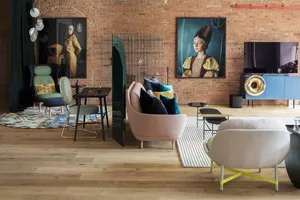 Modern living room with a wooden floor, brick walls, and colorful furniture.