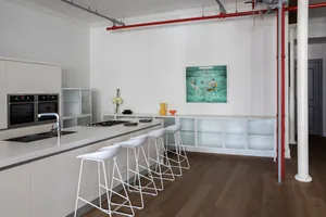 Modern minimalist kitchen featuring sleek white cabinets, a clean white countertop, and a white industrial-style bar with sto