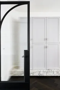 Modern kitchen with white marble countertops, glass cabinets, and concrete flooring, featuring sleek and minimalist design.