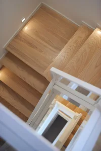 A wooden staircase with white railings and a light wooden floor.