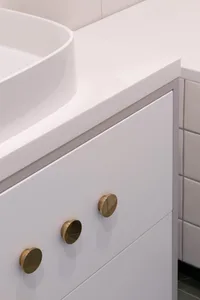 A close-up image of a modern white bathroom vanity with matte-finish handles and a white countertop.