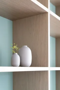 Two minimalist ceramic vases on a wooden shelf.
