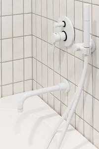Modern bathroom with white ceramic tiled walls, metal faucet, and white bathtub.