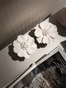 Decorative ceramic floral pieces with long shadows on a shelf.