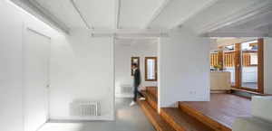 A minimalist apartment with white walls and wooden stairs, showcasing a modern design.