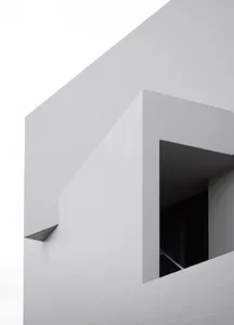 Modern minimalist building featuring a concrete wall with a window cutout.