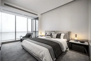 Modern and stylish bedroom with gray bedding and a comfortable seating area in front of large windows.