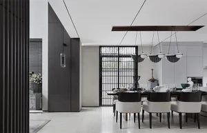 Modern minimalist dining area with concrete walls, glass dining table, and black chairs.
