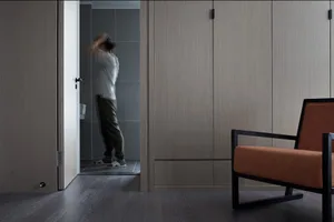 Modern minimalist living room with concrete floor and walls, featuring simple furniture and a single orange armchair.
