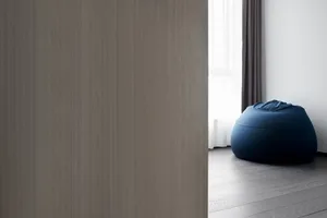 A minimalist living room featuring a blue fabric beanbag on a wooden floor.