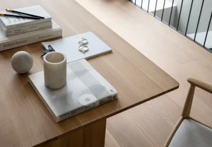 A minimalist workspace featuring wooden surfaces and simple objects on a desk.