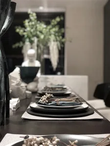 Modern dining room setting with ceramic plates, greenery, and decorative elements.