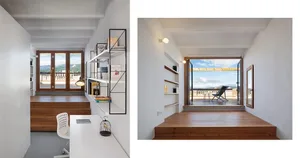 Modern home office featuring a desk, bookshelf, and floor-to-ceiling window overlooking a balcony and landscape.