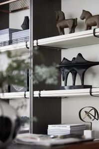 A modern metal shelf with books, horse sculptures, and abstract sculptures.