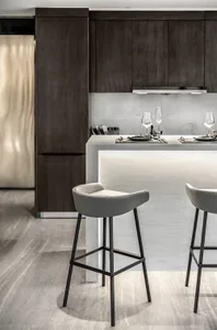 Modern kitchen with marble countertops and dark cabinets, featuring sleek bar stools and a minimalist design.