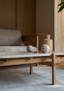 A modern living room with a wooden sofa, marble coffee table, and decorative spheres and vase.