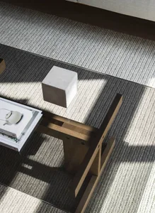 A minimalist living room with wooden furniture, glass coffee table, and white carpet.