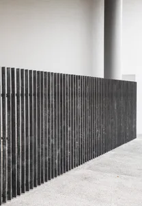 A modern minimalist wall composed of parallel metal rods.