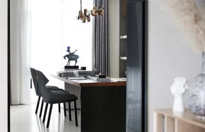 A modern office space featuring a sleek desk with stacks of books, chairs, and a decorative horse statue on a desk.