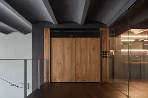 Modern residential entryway featuring wooden doors, metallic accents, and glass panels.