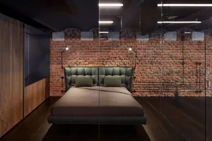 Modern bedroom with industrial design featuring a bed made of leather and metal, with a brick wall and wooden floor.