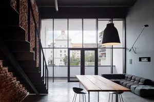 A spacious industrial living room with concrete and wooden furniture.